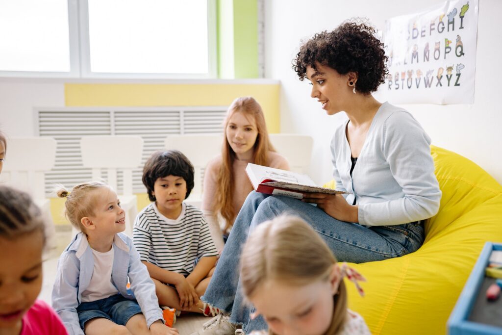 Kindergartenlehrerin liest Kindern aus Buch vor.